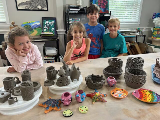 Children proudly display their handmade clay pottery and colorful crafts.