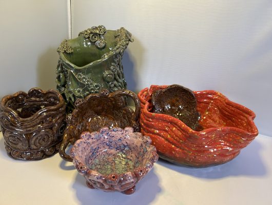 A collection of colorful handmade ceramic bowls with various textures and shapes.
