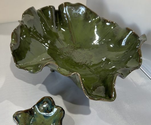 Green ceramic bowl with an organic, leaf-like shape and glossy finish.